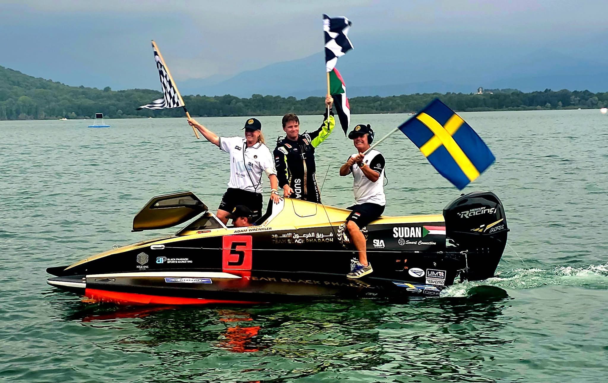 Black Pharaoh team on a number 5 racing boat waving flags